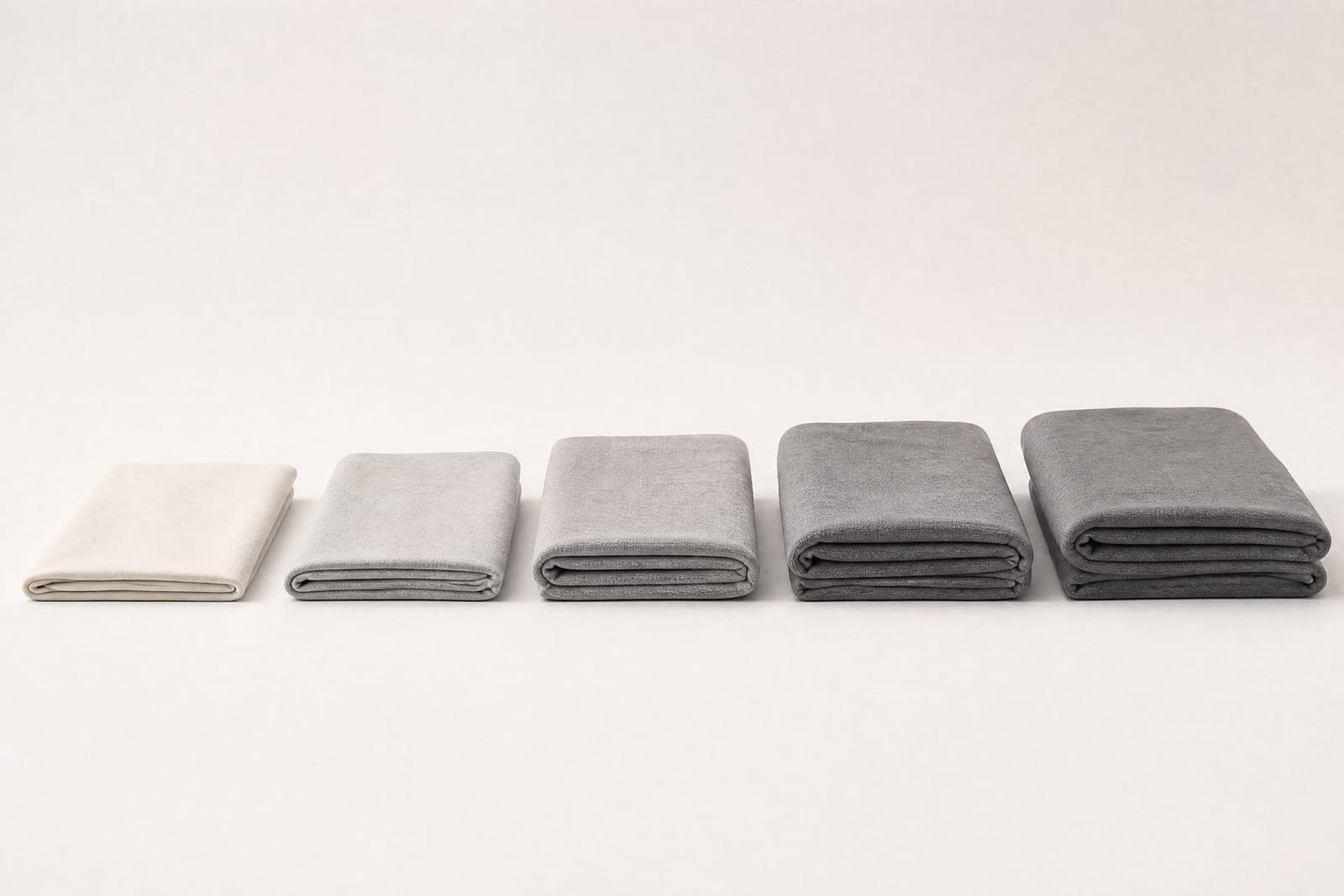 Five folded squares of jersey of increasing thickness, lit from the side