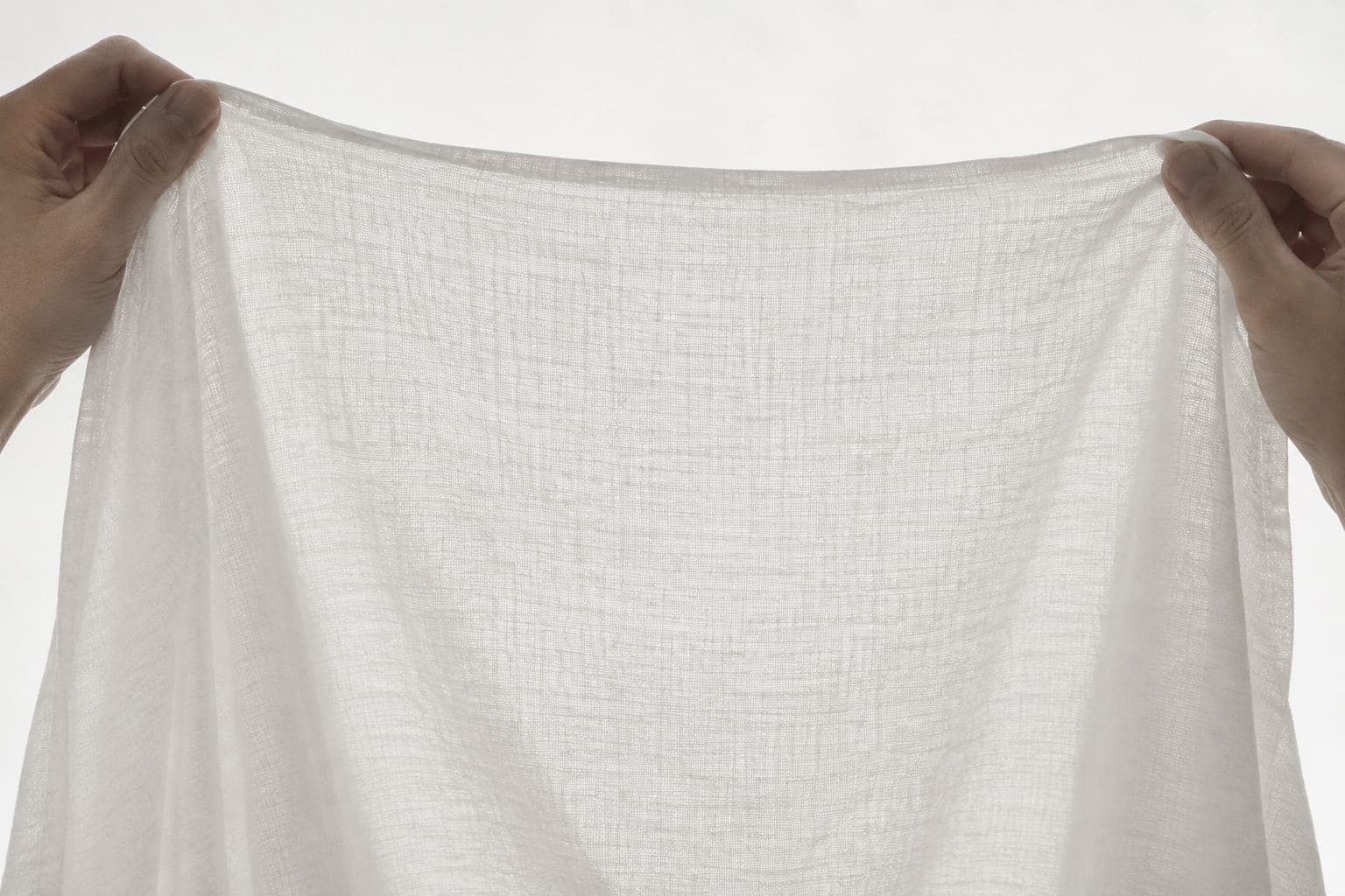 Lightweight jersey held against a backlight, showing light passing through
